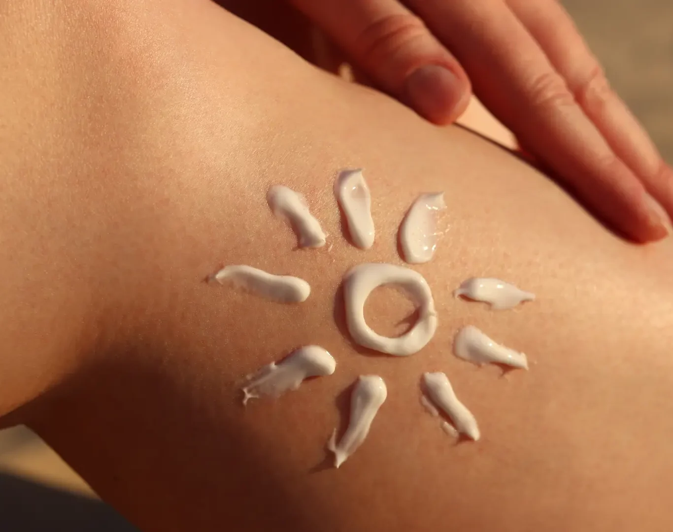 an image of a person's leg with a drawing of a sun using lotion for a blog post about sun damaged skin