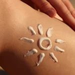 an image of a person's leg with a drawing of a sun using lotion for a blog post about sun damaged skin